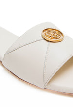 Load image into Gallery viewer, White sandal with a gold emblem on a white background
