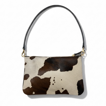 Cow print handbag with a black handle on a white background