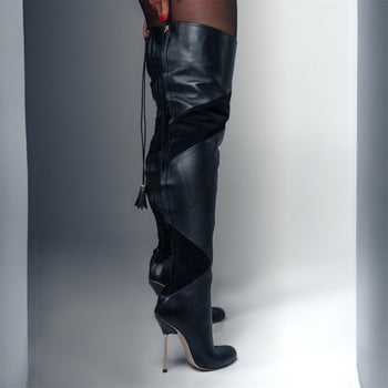 Black leather knee-high boots with a unique design on a gray background