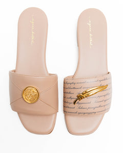 Pair of beige slides with gold accents on a white background