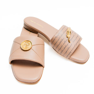 Pair of beige sandals with gold accents on a white background